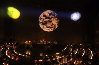 Innenraum der katholischen Kirche Heilige Familie in Düsseldorf-Stockum während der Lesungen in der Osternacht - die Illumination zeigt passend zur "Erschaffung der Welt" Erde, Sonne und Mond